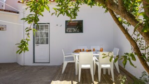 A patio with white chairs and a table, a white door, and a small window with a view. - Quinta Alegria - Rustic Cottage (Alcobaça)