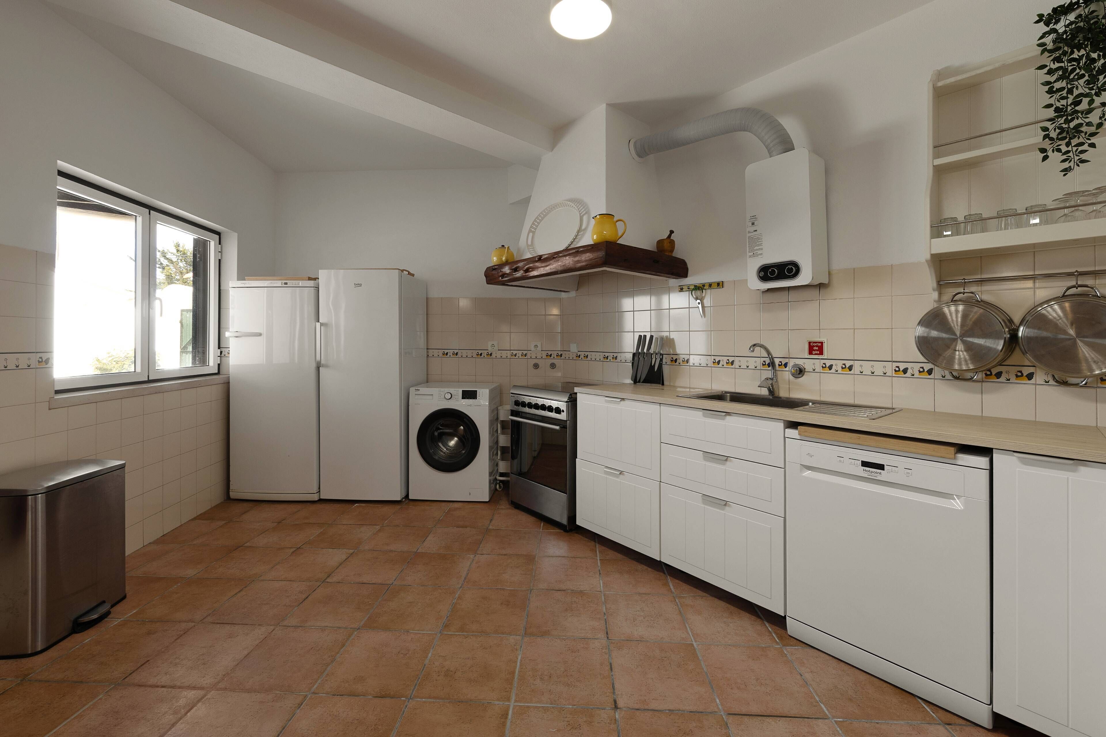 Cuina amb rentadora, forn, rentavaixelles i una finestra.