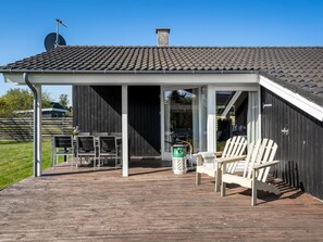 Un espacio al aire libre techado con una terraza de madera, una parrilla y asientos exteriores.