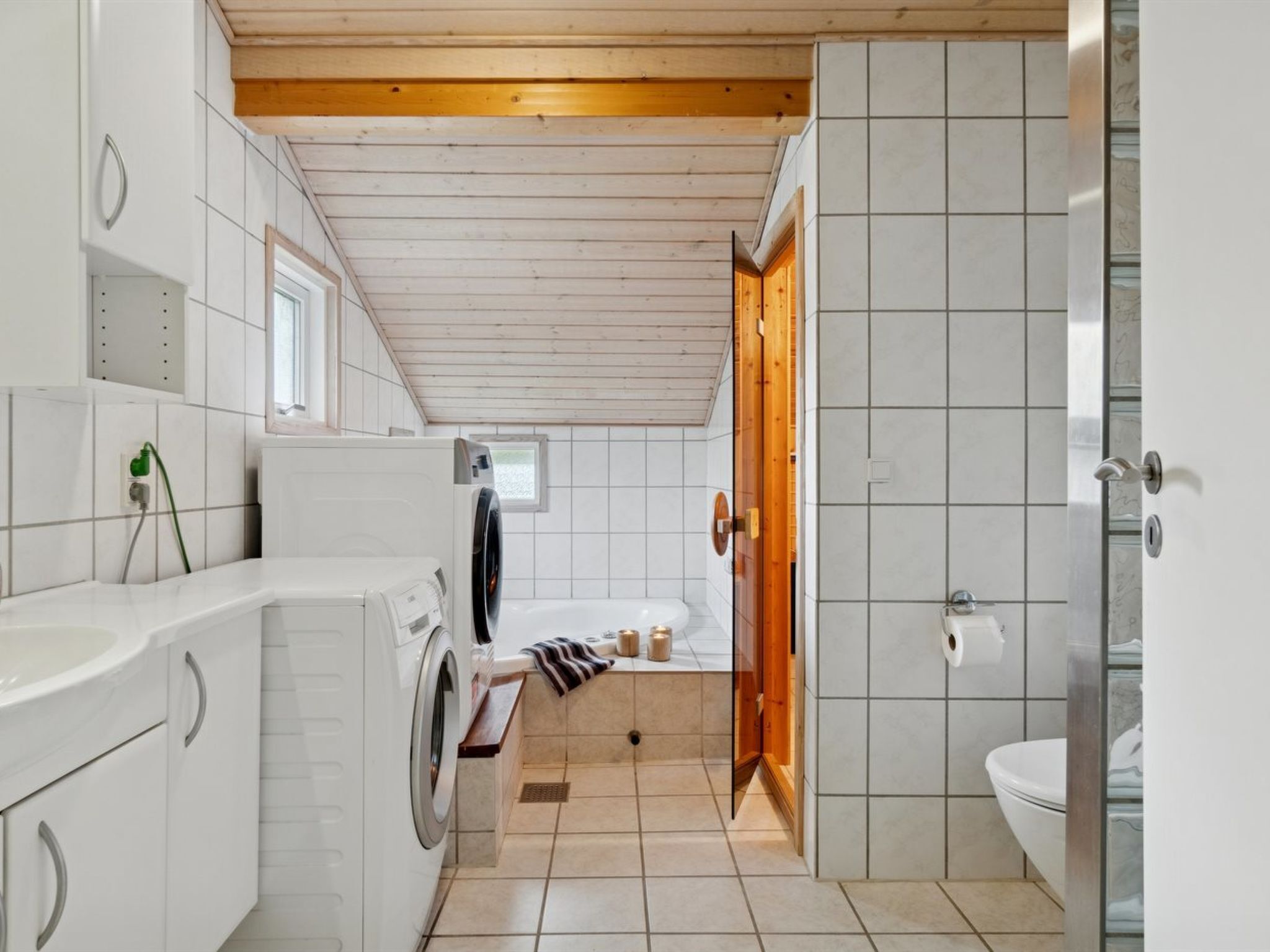Et lille badeværelse med vaskemaskine, toilet og håndvask.