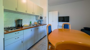 A compact kitchen with a gas stove, microwave, and a dining area with a table and chairs. - Lucas Apartment A3 in Rovinj (Rovinj)