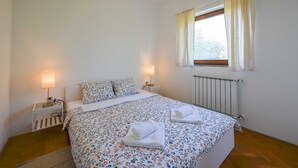 A bedroom with a bed, two bedside lamps, a window with curtains, and a radiator. - Lucas Apartment A3 in Rovinj (Rovinj)