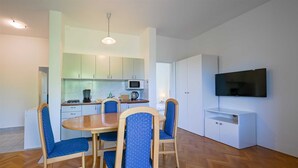 A compact living space with a dining area, kitchenette, and a flat-screen TV mounted on the wall. - Lucas Apartment A3 in Rovinj (Rovinj)