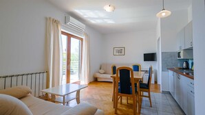 Una camera moderna con un letto, un tavolo da pranzo con sedie, un angolo cottura e un'ampia finestra con tende.