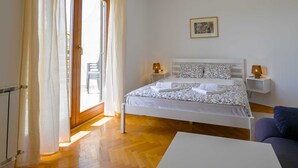 Ein Schlafzimmer mit einem Bett, zwei Nachttischen, einem Sessel und einem Bild an der Wand.