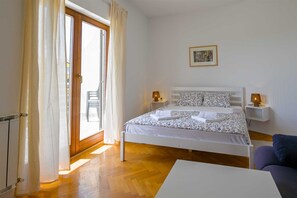 Ein Schlafzimmer mit einem Bett, zwei Nachttischen, einem Sessel und einem Bild an der Wand.