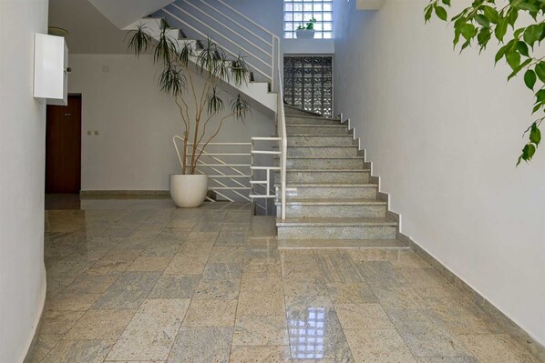 Eine Treppe mit Metallgeländer, einem Blumentopf und einer Tür am Fuß.