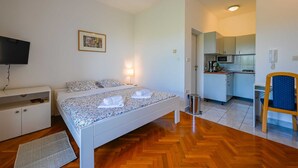 Quarto com cama, televisão, escrivaninha e cadeira.