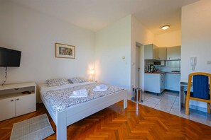 Ein Schlafzimmer mit einem Bett, einem Fernseher, einem Schreibtisch und einem Stuhl.