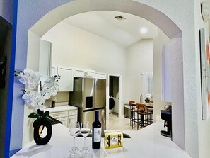 Una cocina moderna con electrodomésticos de acero inoxidable, armarios blancos y un comedor con mesa y sillas.