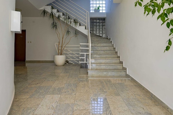 Eine Treppe mit Metallgeländer, einem Blumentopf und einer Tür am Fuß.