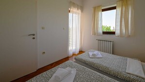 A room with two beds, a window with curtains, a radiator, and a door. - Lucas Apartment A8 In Rovinj (Rovinj)