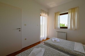 A room with two beds, a window with curtains, a radiator, and a door. - Lucas Apartment A8 In Rovinj (Rovinj)