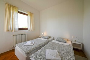 A bedroom with two beds, a window with curtains, a radiator, and bedside lamps. - Lucas Apartment A8 In Rovinj (Rovinj)