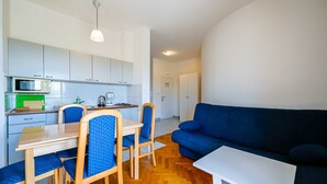 A compact living space with a kitchenette, dining area, and a blue sofa. - Lucas Apartment A8 In Rovinj (Rovinj)