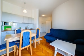 A compact living space with a kitchenette, dining area, and a blue sofa. - Lucas Apartment A8 In Rovinj (Rovinj)