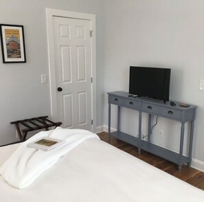 A bedroom with a bed, a dresser, a television, and a door.