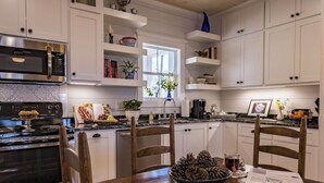 A kitchen with white cabinets, a wooden dining table, and a stainless steel oven.