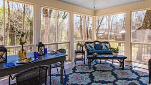 A covered patio with a ceiling fan, a dining table with chairs, a sofa, and a patterned rug.
