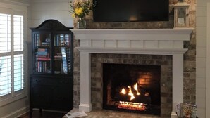 A fireplace with a TV above it, a bookshelf, and a window with blinds.