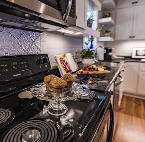 A kitchen with a black stove, a microwave above it, and a digital clock displaying 1:38.