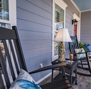 A porch with a table and chairs, a lamp, and a window with shutters.