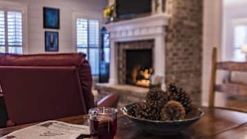 Un coin repas avec une cheminée, une table sur laquelle repose un journal, un verre contenant une boisson rouge et un bol rempli de biscuits.
