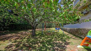 A playground with swings and a slide, surrounded by grass and trees. - Lucas studio A9 in Rovinj (Rovinj)