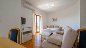 A room with a sofa, a table, a bed, a TV, and a window with curtains. - Lucas studio A9 in Rovinj (Rovinj)