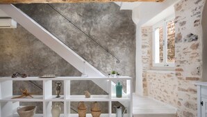 Une pièce avec un escalier blanc, un mur en béton et une fenêtre donnant sur un paysage.