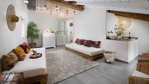 Une pièce confortable avec un lit, un petit canapé, une commode blanche, un miroir et un luminaire suspendu.