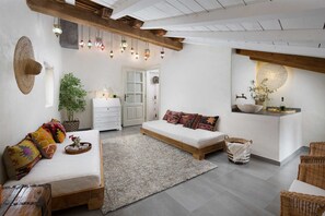 Ein gemütliches Zimmer mit einem Bett, einer kleinen Couch, einer weißen Kommode, einem Spiegel und einer Pendelleuchte.