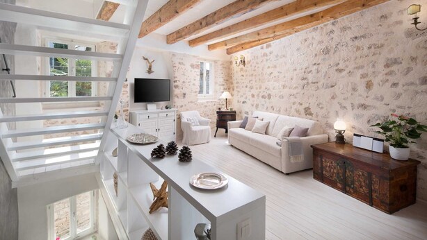 Un salon moderne avec un canapé blanc, une table basse en bois et un téléviseur posé sur un meuble blanc.