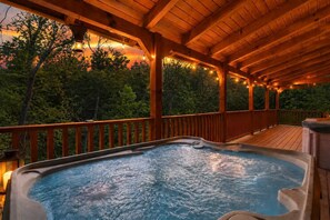 A hot tub on a wooden deck with a view of trees and a sunset. - Mountain Escape w/ Hot Tub & Game Room (Sevierville)