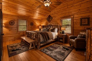 A log cabin bedroom with a bed, a chair, a desk, and a window. - Mountain Escape w/ Hot Tub & Game Room (Sevierville)