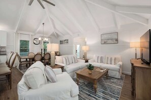 A spacious living area with a high ceiling, a dining set, a sofa, a coffee table, and a television. - The Last Mango, Dog Friendly, Pool & Hot Tub (Southern Shores)