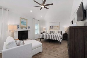 A bedroom with a bed, a TV, a ceiling fan, and a fireplace. - Dog Friendly, Heated Pool, Hot Tub, 5Min to Beach! (Southern Shores)