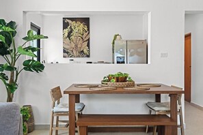 A dining area with a wooden table, two chairs, a bench, and a large plant. - Villa Bali: Private Pool | 2 Min Walk to Beach (San Juan)