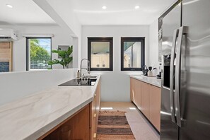 A modern kitchen with a stainless steel refrigerator, a sink, and a window overlooking a residential area. - Villa Bali: Private Pool | 2 Min Walk to Beach (San Juan)