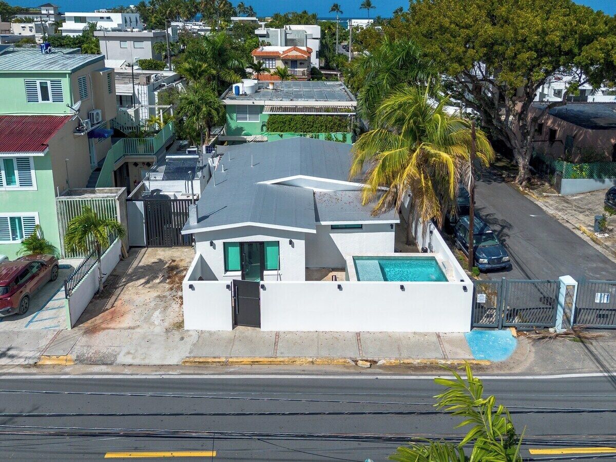 Zona residencial con una casa que cuenta con piscina, un acceso vehicular con portón y vista a la calle.