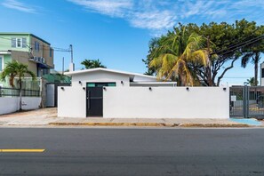 A residential building with a white exterior, a black door, and a gated entrance. - Villa Bali: Private Pool | 2 Min Walk to Beach (San Juan)
