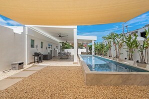 A modern outdoor pool area with a covered seating area, a barbecue setup, and potted plants. - Villa Tropical: Private Pool | 2 Min Walk to Beach (San Juan)