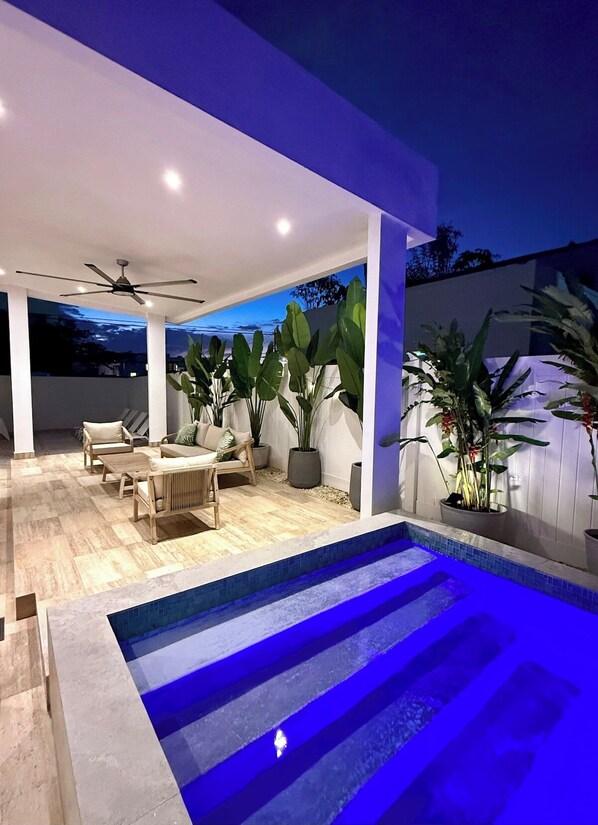 An outdoor pool area with a ceiling fan, seating, and potted plants. - Villa Tropical: Private Pool | 2 Min Walk to Beach (San Juan)