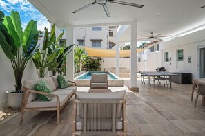Un espace de vie extérieur doté d’une piscine, de sièges et d’un ventilateur de plafond.