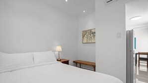 Un dormitori amb un llit gran, una taula de nit, una làmpada i un quadre a la paret.