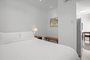 A bedroom with a large bed, bedside table, lamp, and a painting on the wall. - Villa Tropical: Private Pool | 2 Min Walk to Beach (San Juan)
