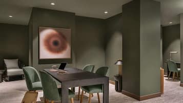 A modern conference room with a dark table, green chairs, a large abstract painting, and a carpeted floor.
