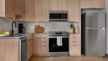 Une cuisine moderne dotée de meubles en bois, d’un réfrigérateur en acier inoxydable, d’un four à micro-ondes, d’un four traditionnel et d’un lave-vaisselle.