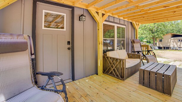 Un portico coperto con una panca di legno, un tavolo e una porta.