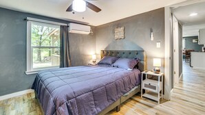 Una camera da letto con un letto, una ventola a soffitto, una finestra e un comodino.